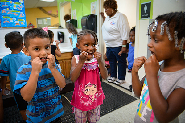 Felix Perlata, 4, Alani Waiters, 5, and Cymia Martin, 4, floss their teeth before heading back to class at Morton Clark Head Start preschool in Bradenton, Fla.