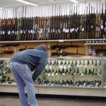 person looking through a gun section at a store. red flag law featured image