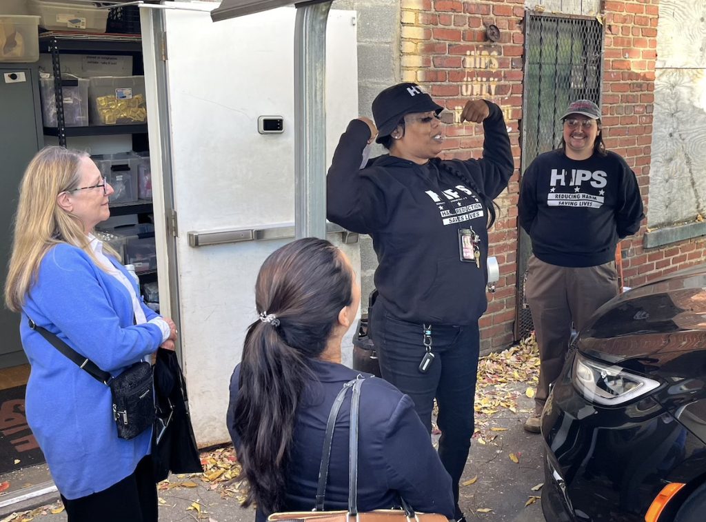 woman standing outside lifting her arms up talking to journalists