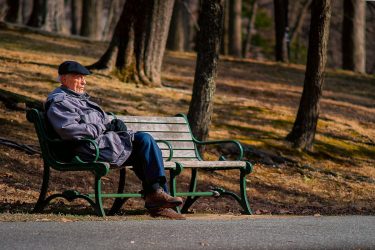an older adult sitting on a park bench