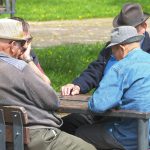 older adults playing dominoes at a table | longevity featured image