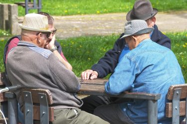 older adults playing dominoes at a table | longevity featured image