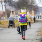 child with colorful backpack walking to school