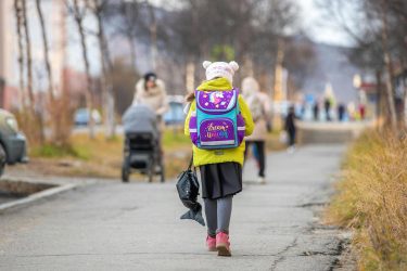 child with colorful backpack walking to school