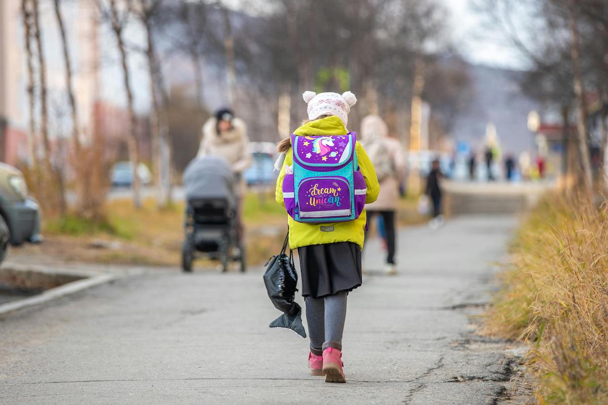 child with colorful backpack walking to school