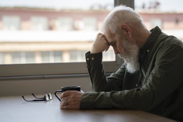 an older man sitting at a table with his head on his hand