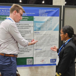 This image depicts Epidemic Intelligence Service (EIS) Officers, Class of 2023, Steven Langerman, MD (left) and Souci Louis, VMD (right), as they were discussing Officer Louis’ poster detailing barriers to COVID-19, and influenza outpatient antiviral treatment perceived by ID specialists, during the 2024 Los Angeles, California IDWeek meeting.