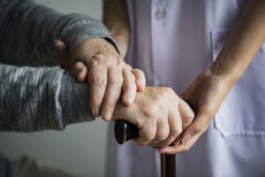 a caregiver at a nursing home holds the hands of an older adult.