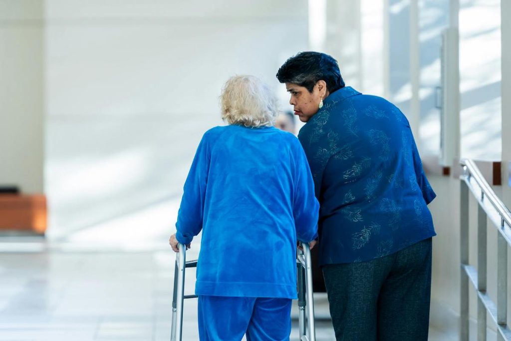 A woman with an older woman with a walker in the hospital. family caregiving featured image