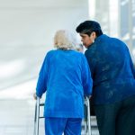 A woman with an older woman with a walker in the hospital. family caregiving featured image