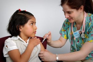 a young girl receives a vaccination from a nurse