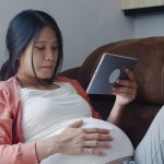 young pregnant woman looking at a tablet. gestational diabetes featured image