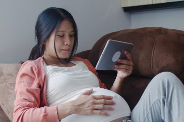 young pregnant woman looking at a tablet. gestational diabetes featured image