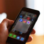 hand holding a smart phone with social media apps on it. youth gun violence featured image