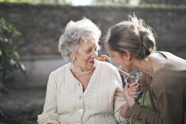 An older woman talking to a younger woman outside. Medicaid HCBS featured photo
