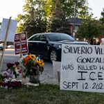 A roadside memorial for Silverio Villegas González, a 38-year-old man who was shot and killed by an unidentified ICE officer in a suburb of Chicago. A prominent sign reads: "Silverio Villegos Gonzalez (RIP) was killed here by I.C.E. Sept. 12, 2025."
