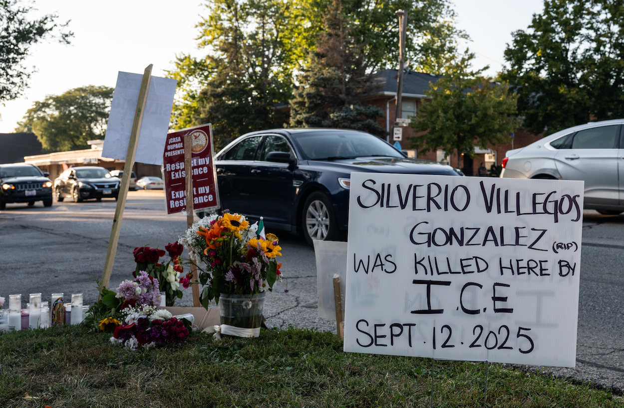 A roadside memorial for Silverio Villegas González, a 38-year-old man who was shot and killed by an unidentified ICE officer in a suburb of Chicago. A prominent sign reads: "Silverio Villegos Gonzalez (RIP) was killed here by I.C.E. Sept. 12, 2025."