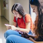 girls on their phones in a school hallway