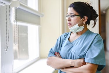 female nurse staring out window. health disparities featured img
