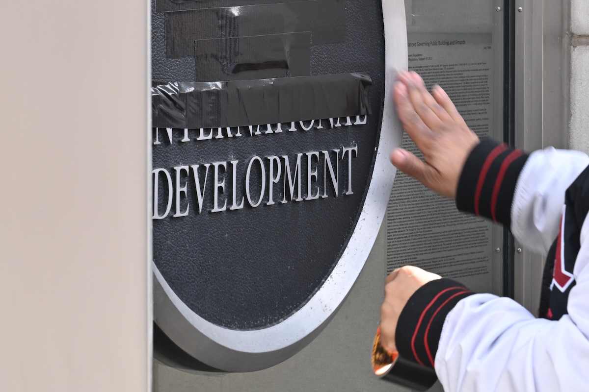 A person tapes over a USAID sign at the agency's main entrance in Washington, D.C., in February 2025.