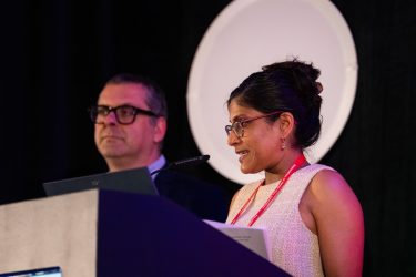 AHCJ Contest Committee Co-Chair Renuka Rayasam announces winners at HJ26 next to Committee Co-Chair Jonathan Rockoff. Photo by Zachary Linhares