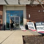 Voting signs outside of a polling location. The signs say "VOTE HERE DISTRICT 12" and "VOTE HERE DISTRICT 5"