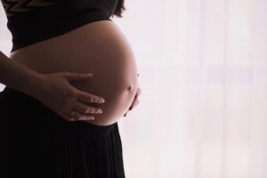 Pregnant woman holding her belly. Taking the Tdap vaccine during pregnancy is still the most effective way to prevent whooping cough in infants.