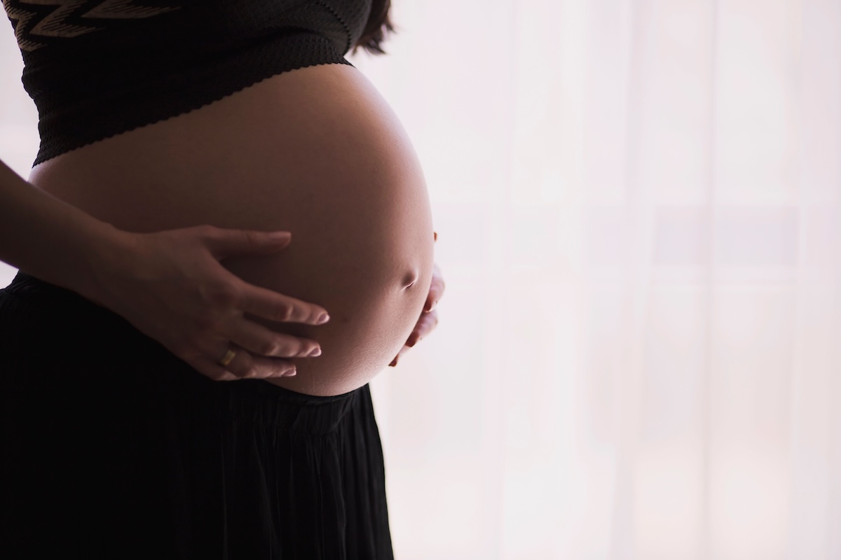 Pregnant woman holding her belly. Taking the Tdap vaccine during pregnancy is still the most effective way to prevent whooping cough in infants.