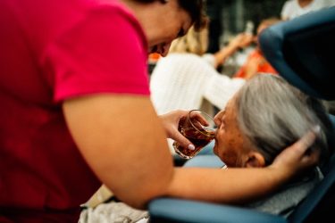 Family caregiver helping a dementia patient drink.