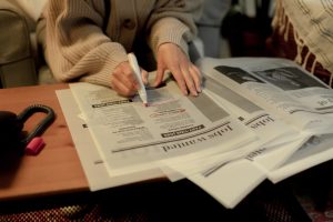 a person who was laid off searching a newspaper classifieds