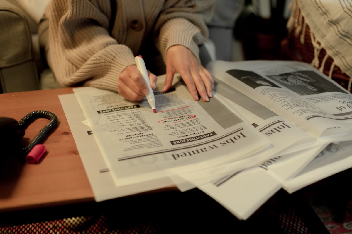 a person who was laid off searching a newspaper classifieds