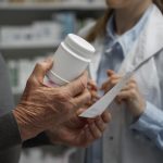 An older man talks to a pharmacist about increased prices in Medicare plan