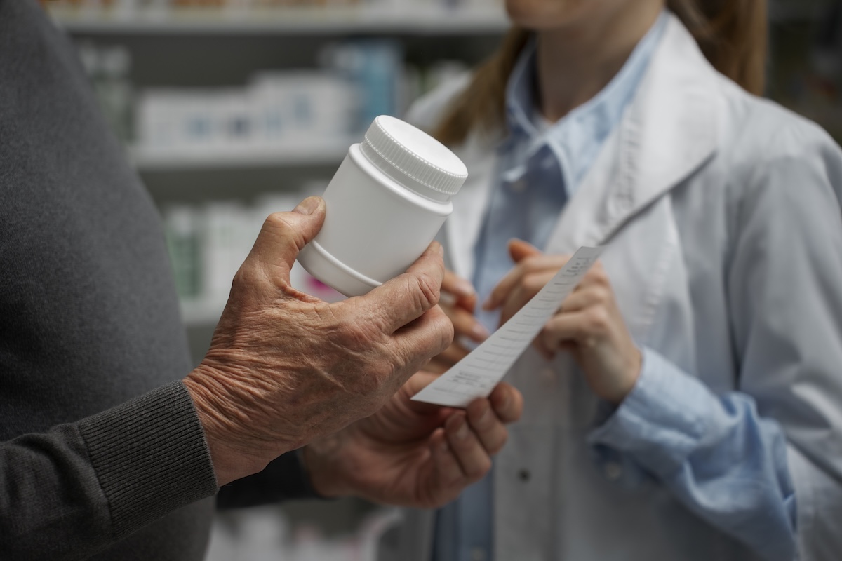 An older man talks to a pharmacist about increased prices in Medicare plan