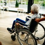 an older adult in a wheelchair being pushed by a person in an end-of-life care facility
