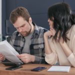 a stressed couple looking at hospital bills and high insurance premiums