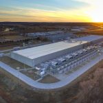 This data center is located in Council Bluffs, Iowa, and is operated by Google. The facility houses rows of exterior cooling and generator equipment along its southern side, supporting server operations inside the building. Council Bluffs has hosted a Google data center campus since 2007, one of the company's earliest large-scale server facility investments in the United States. The site sits near the Missouri River on the western edge of Iowa, adjacent to industrial and agricultural land. AI and public health