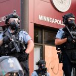 Minneapolis Police in front of their sign at 3rd Precinct