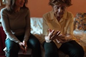 an older woman and her daughter. the older woman is looking at her wedding ring sadly. nursing home oversight