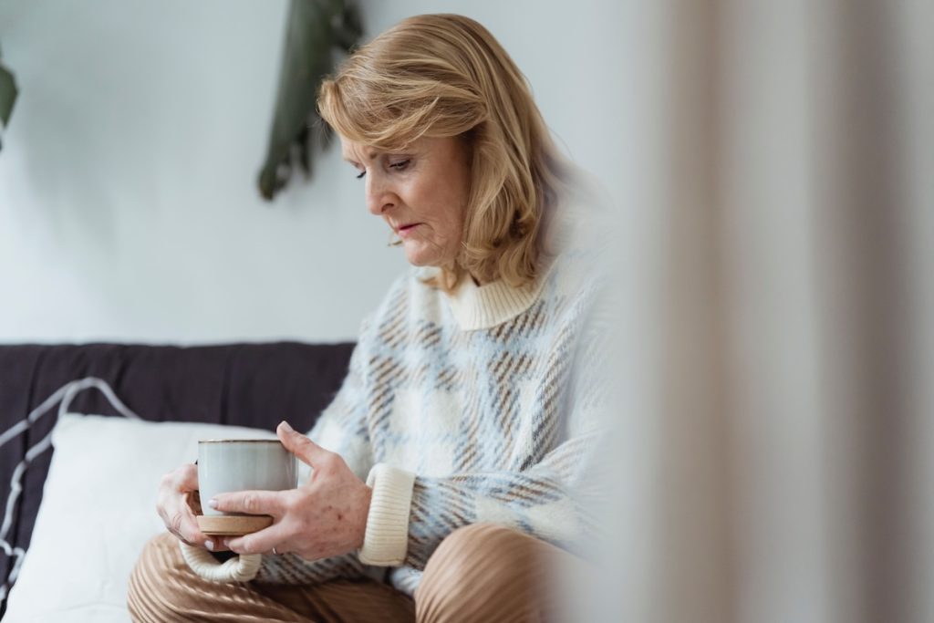 an older woman holding a mug